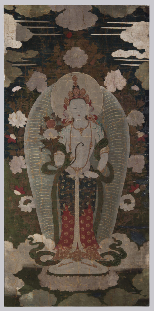 Bodhisattva wearing blue and red brocade dhoti stands, holding long-stemmed blossom, amongst clouds and blossoms