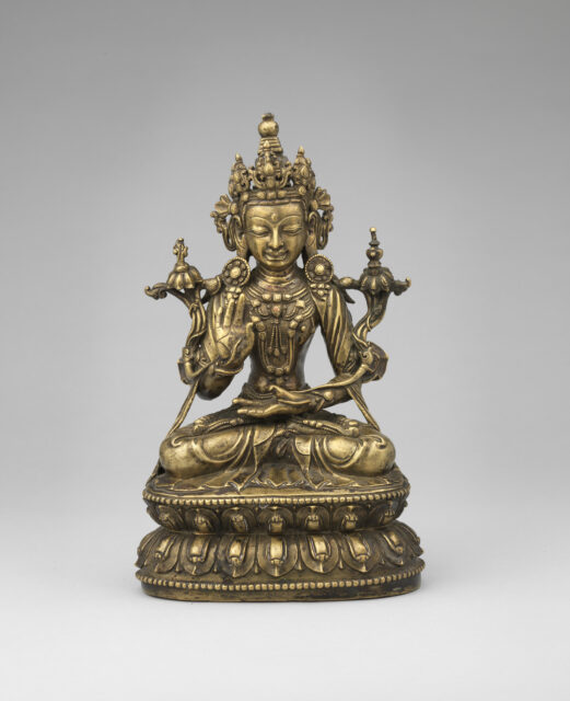 Bronze-colored statue depicting seated Bodhisattva wearing ornate crown and pleated dhoti holding long-stemmed blossoms
