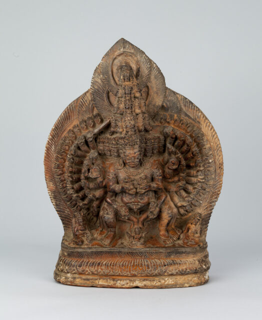 Ruddy-brown sculpture depicting deity with countless heads and arms arranged in semi-circles at sides of body