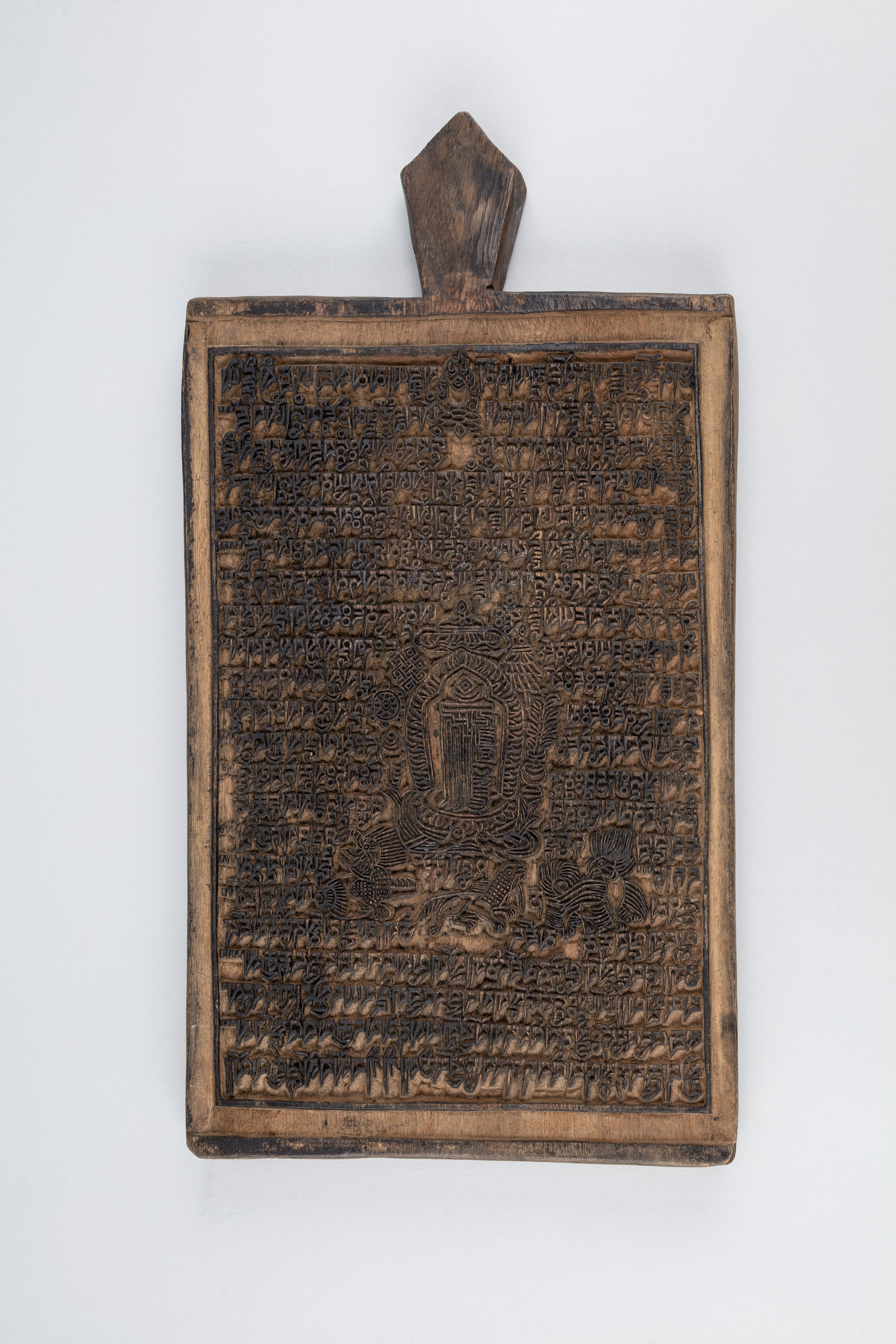 Rectangular ink-stained woodblock incised with dense text and image; lozenge-shaped handle at top