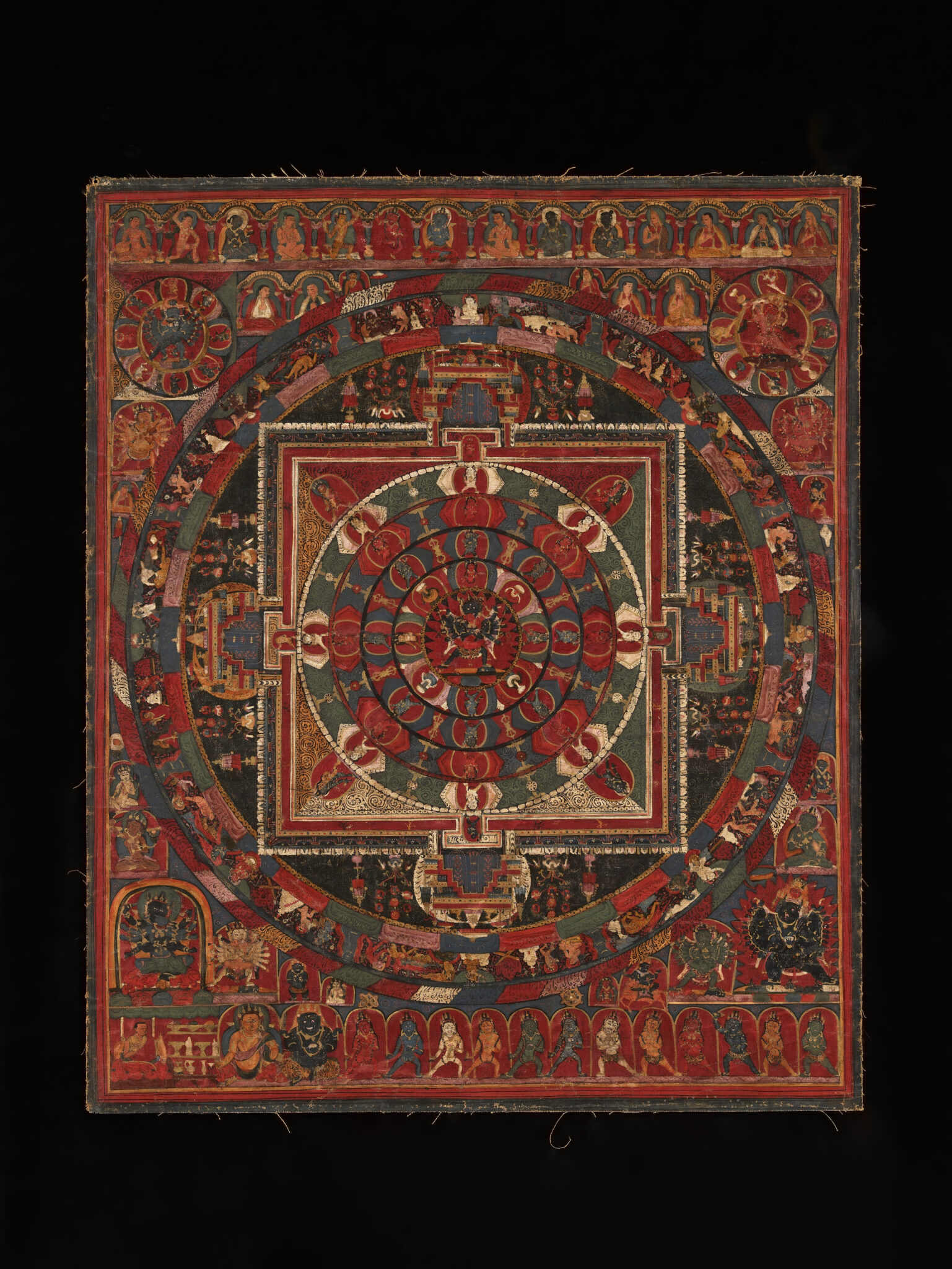 Mandala in rust-reds and greens featuring vajra-pointed inner circle and deity portraits at corners