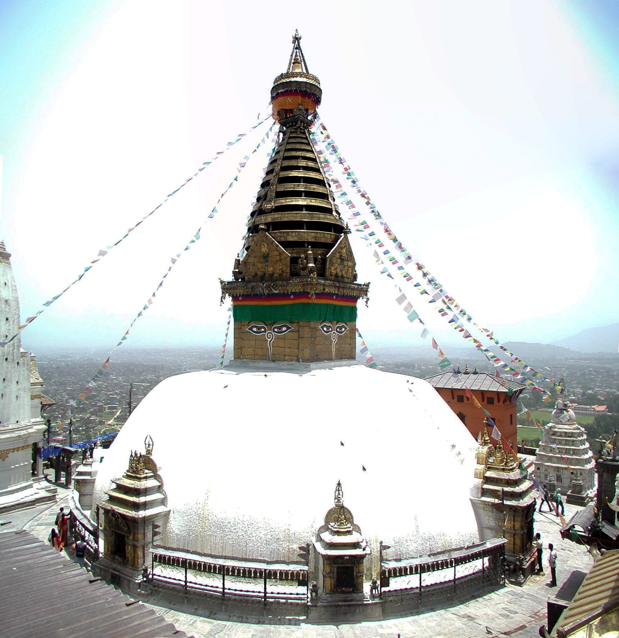 Prayer flags descend from the peak of stupa (conical tower atop bright white dome)