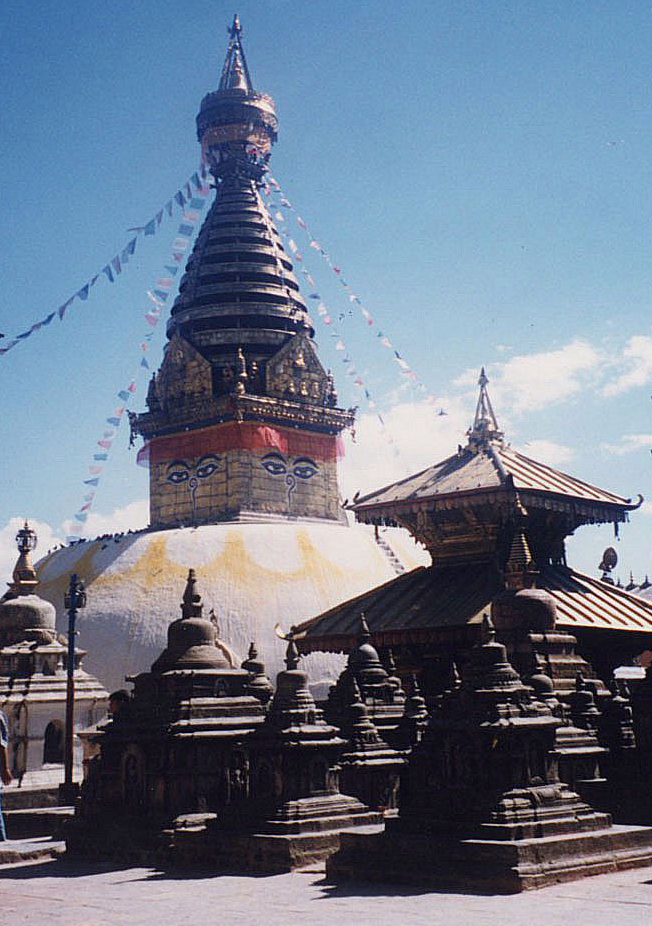 Large stupa (dome topped with conical tower) rises behind group of smaller stupas and pagoda
