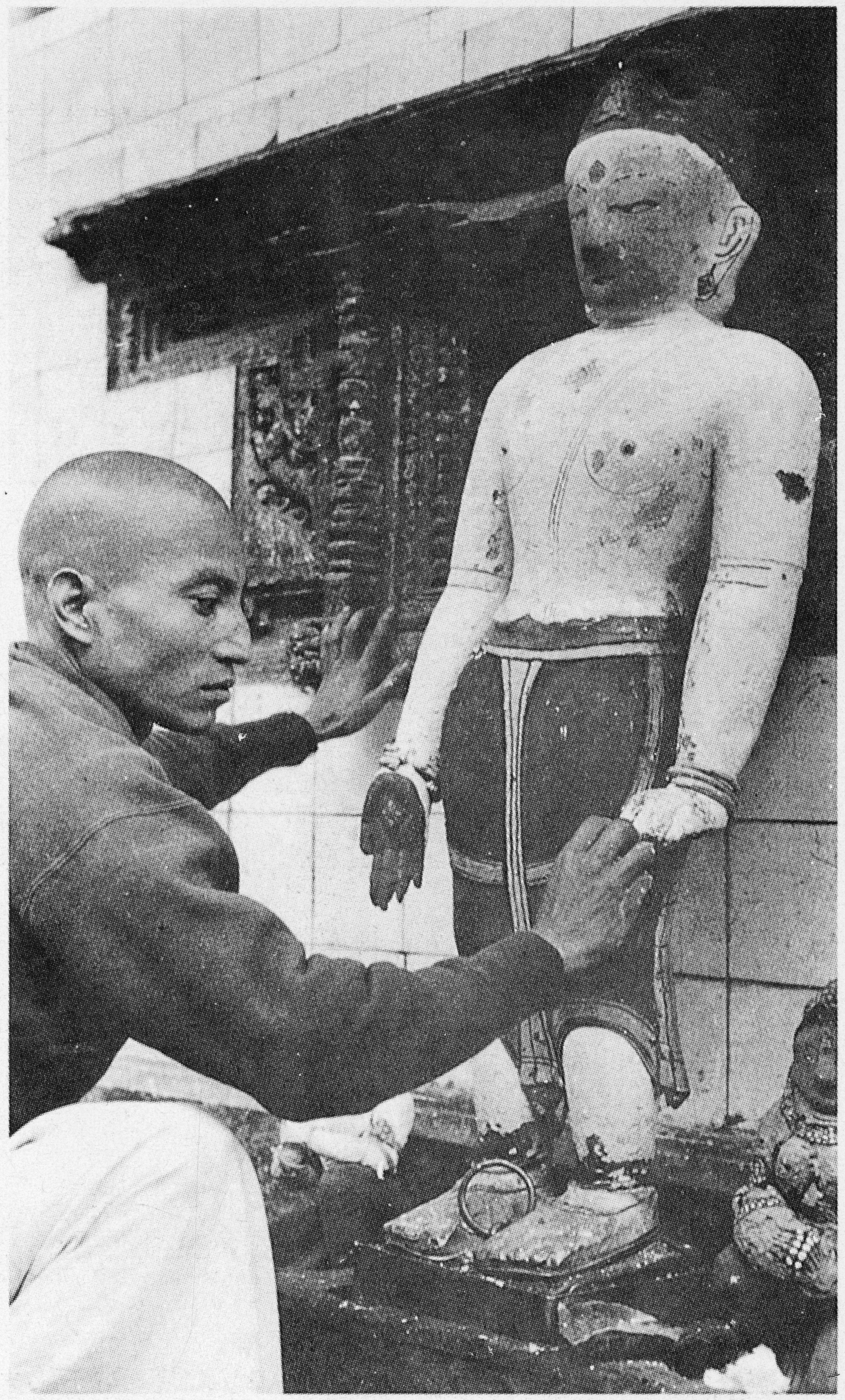 Black and white photograph of man touching hand of Bodhisattva statue