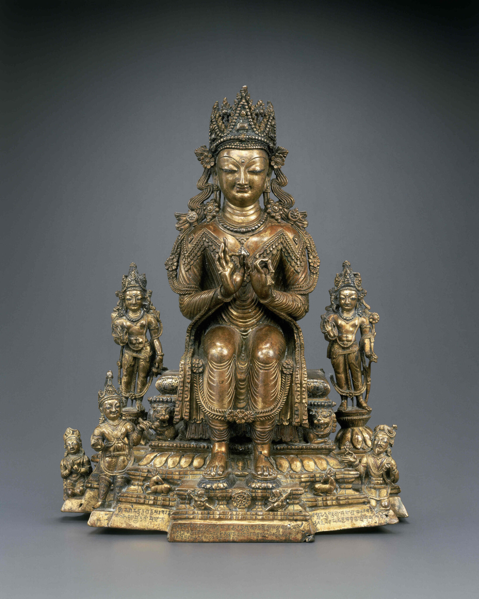 Intricately detailed brass statuette of enthroned Buddha flanked by five smaller deities