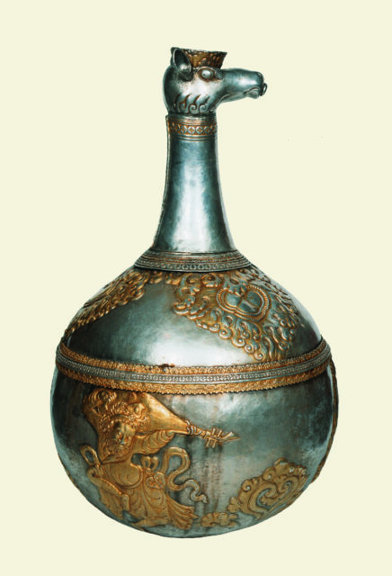 Globe-shaped silver vessel featuring long neck and animal head spout; decorated with golden figures and patterns