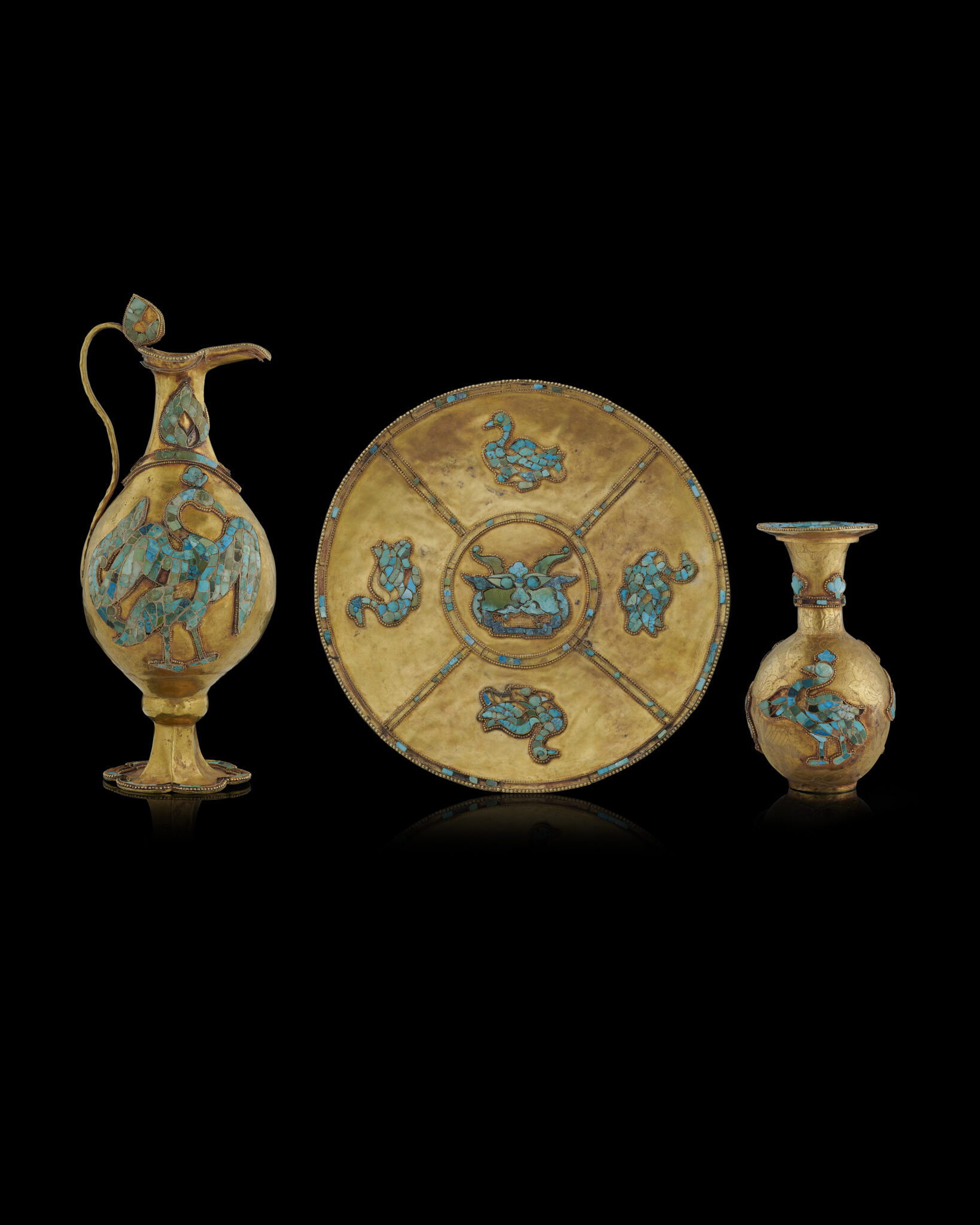 Three golden dinnerware pieces (ewer, plate, decanter) decorated with birds set in turquoise stones