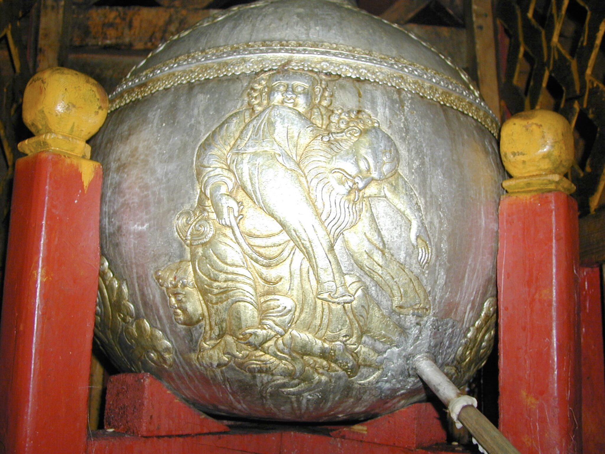Close view of bottom hemisphere of spherical silver vessel decorated with trio of men in inebriated state