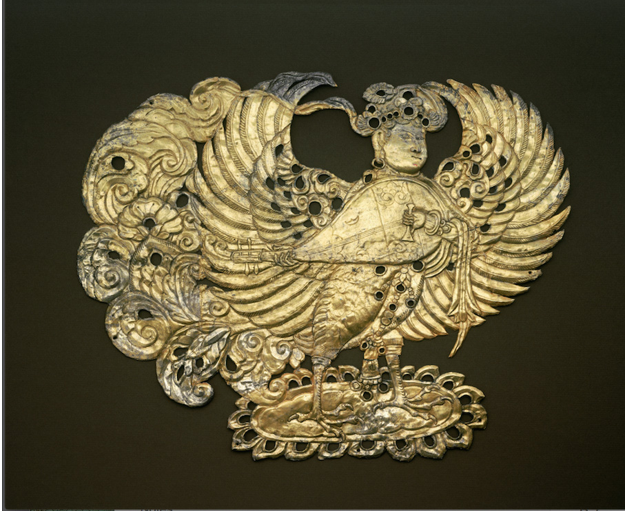 Tarnished golden-silver plaque depicting human/bird deity playing stringed instrument with outstretched wings