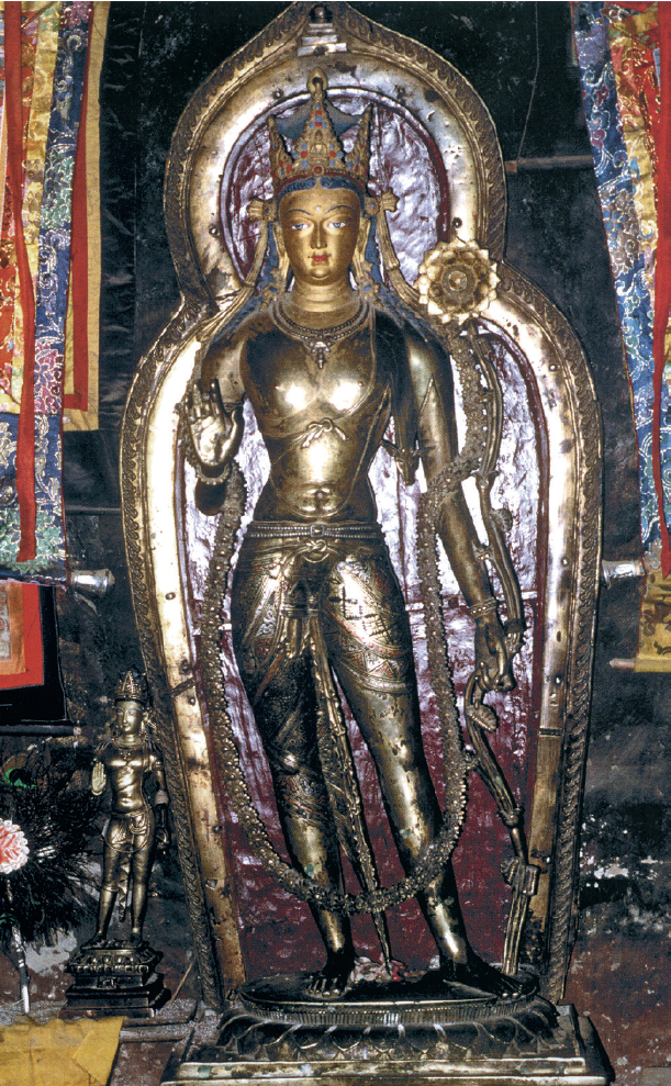 Statue of Bodhisattva with red and gold nimbus standing amid colorful banners alongside smaller deity statue