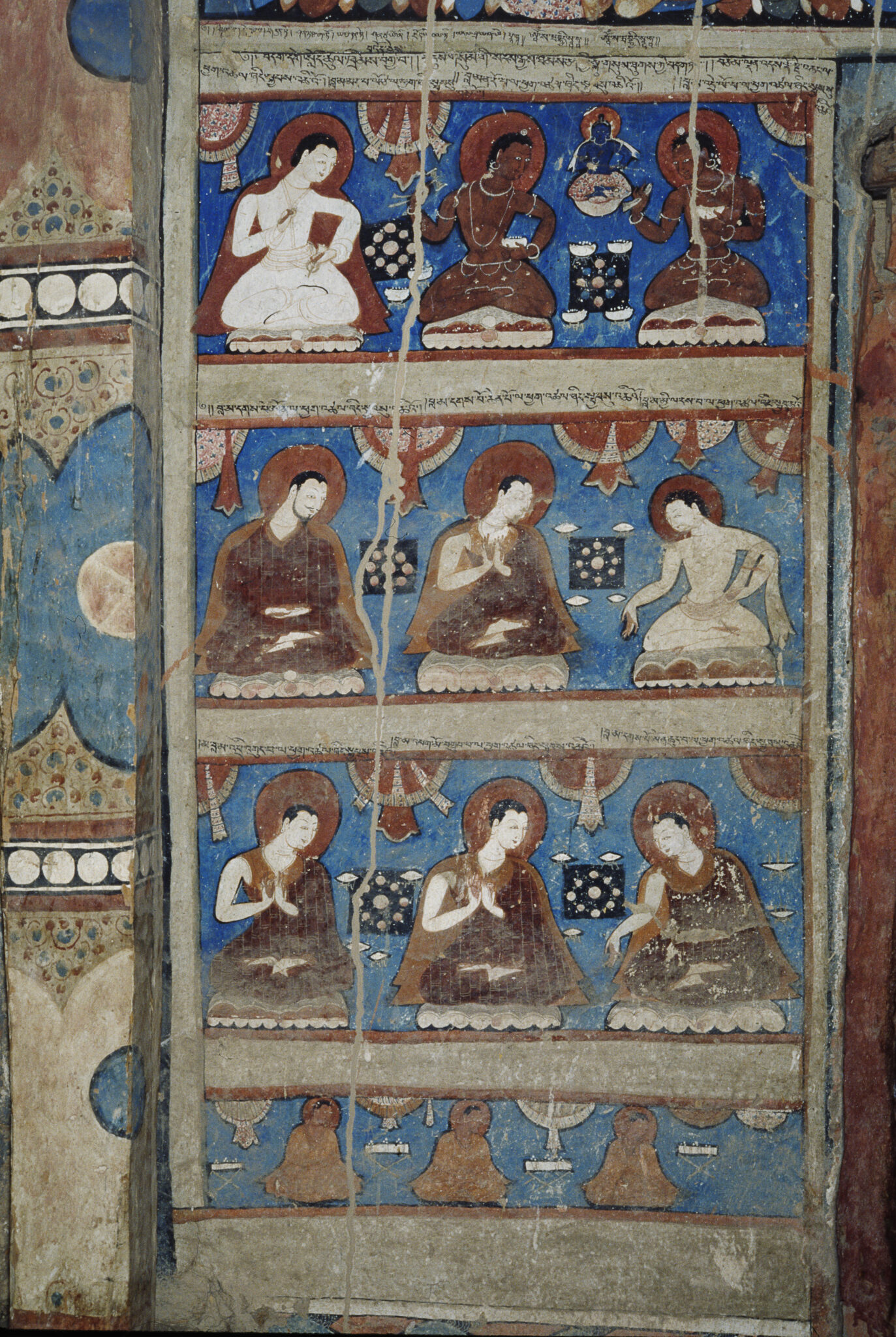 Nine seated figures arranged in three registers against blue backgrounds above bottom row of three stupas