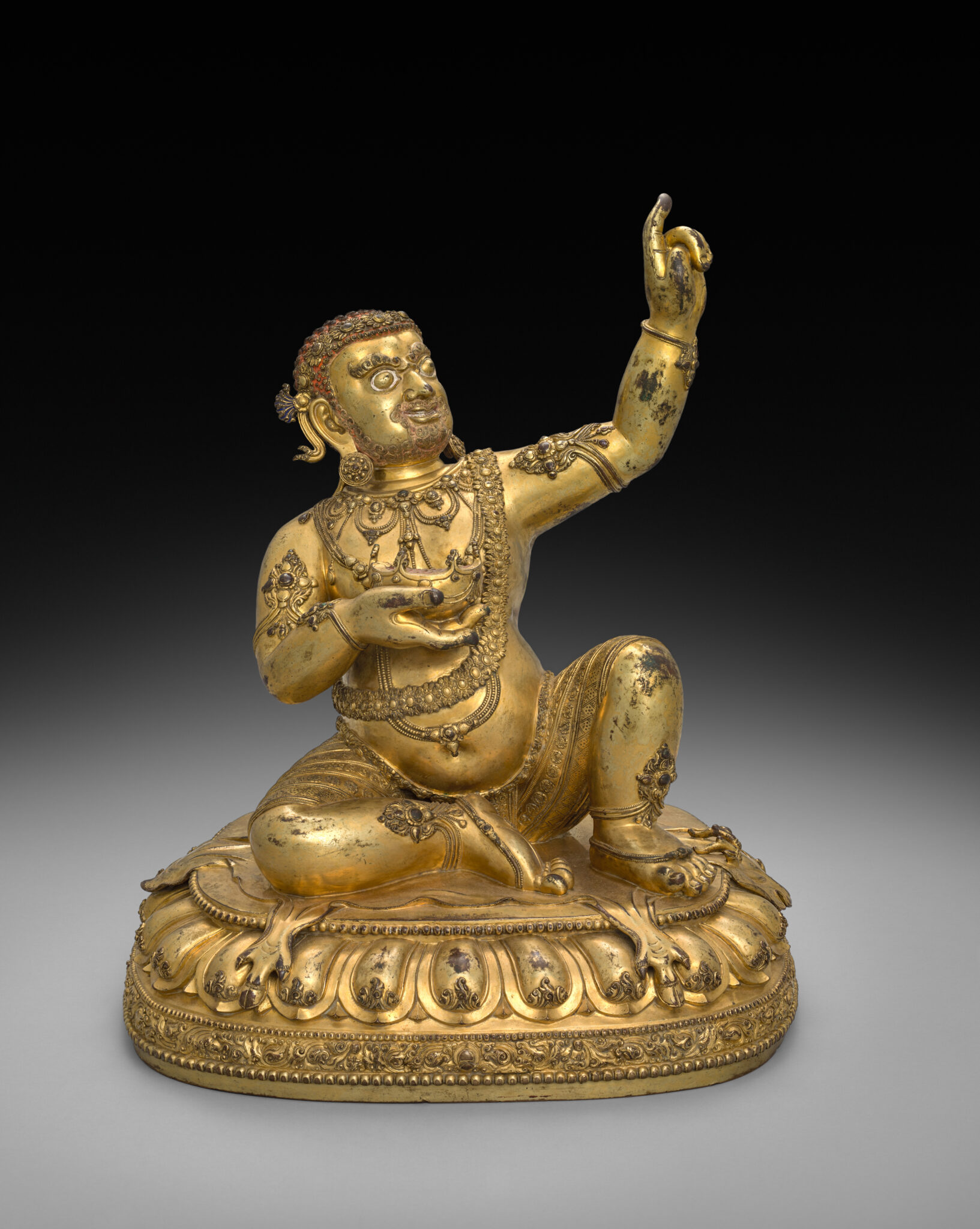 Gilded statuette of figure wearing dhoti seated on lotus pedestal with right arm and knee raised