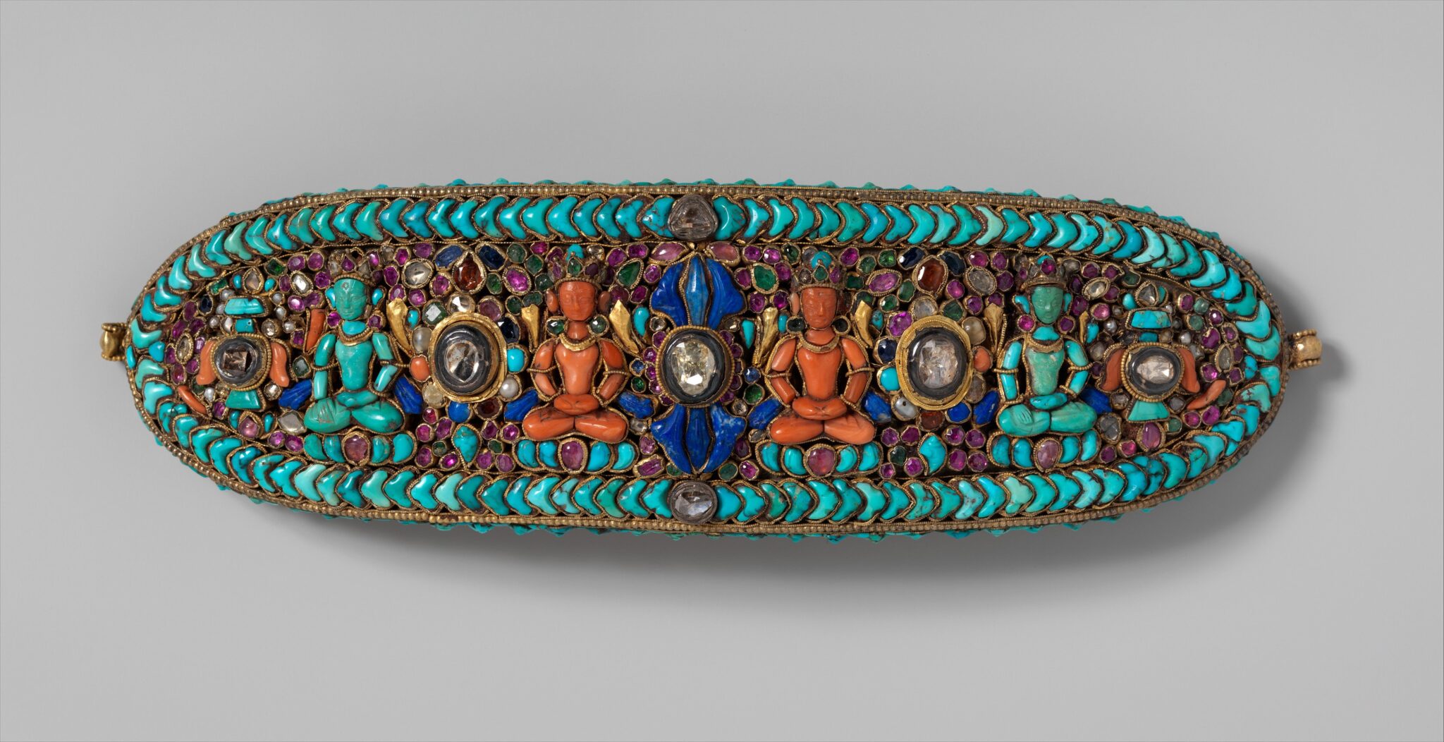 Elliptical ornament depicting four seated deities and vajra; set in turquoise, orange, blue, and purple stones