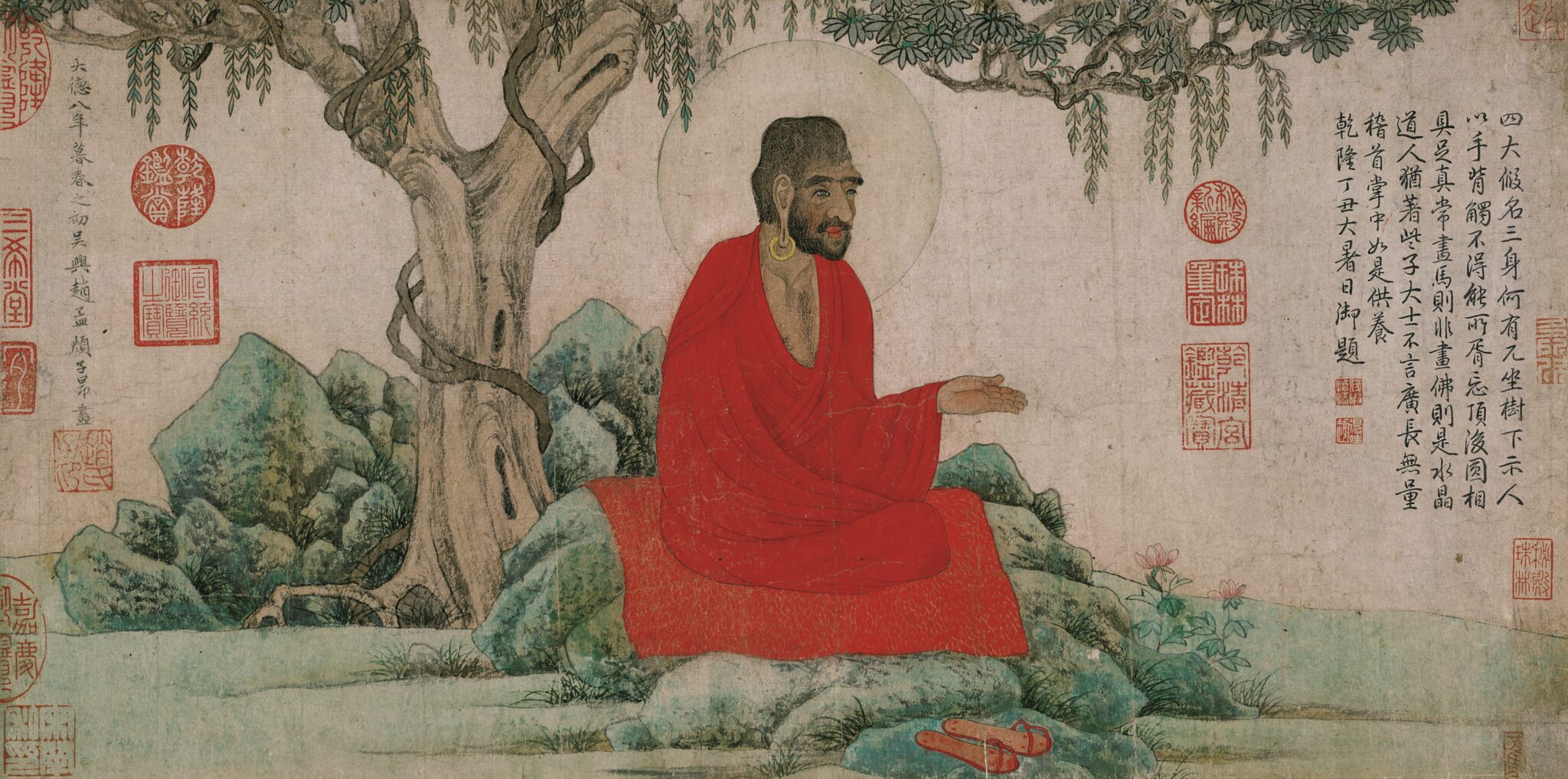 Holy man wearing brilliant red robe seated on green outcropping underneath tree; flanked by Chinese text and seals
