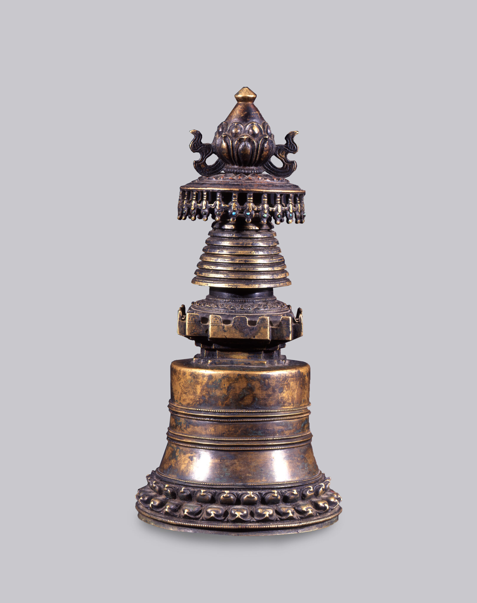Mottled copper religious implement in stupa shape with canopy and lotus blossom at top