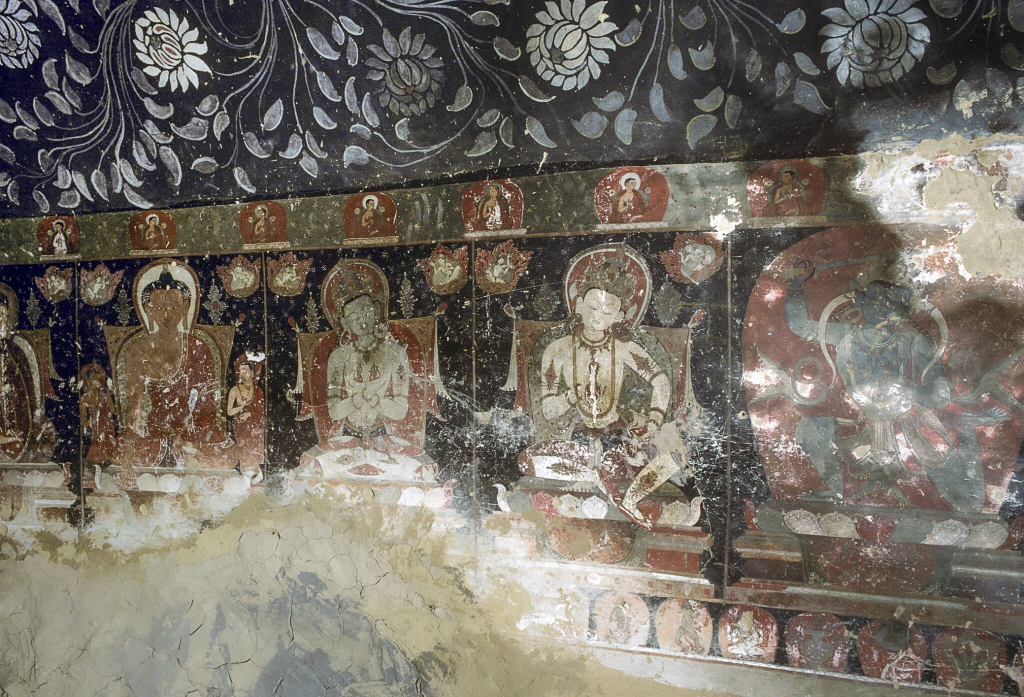Register of deity portraits below floral motif; heavy damage to bottom left section of mural