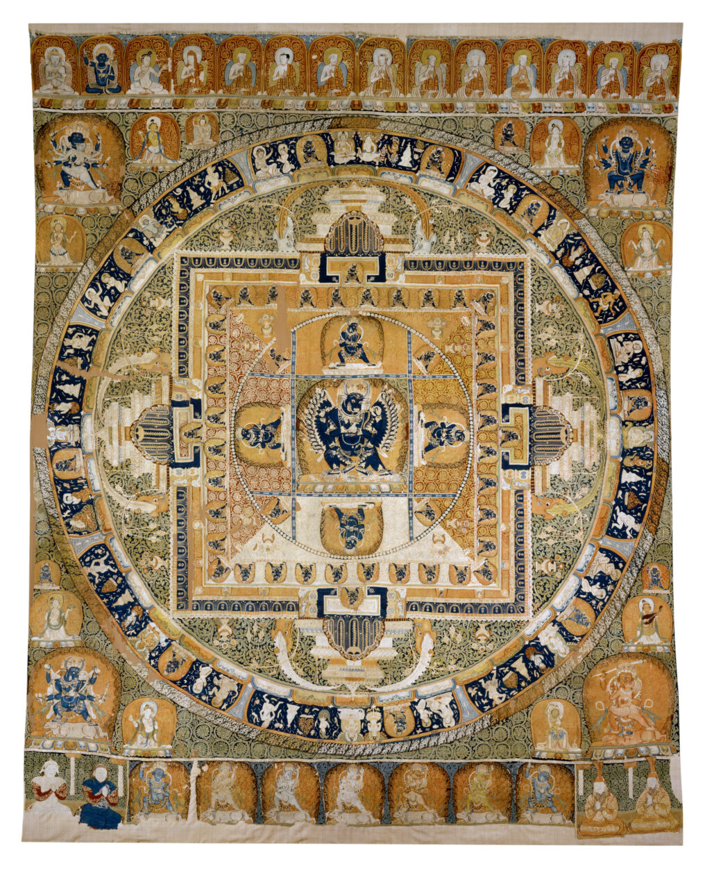 Mandala dominated by yellow, orange, gold, and green tones; features dynamically posed deity at center