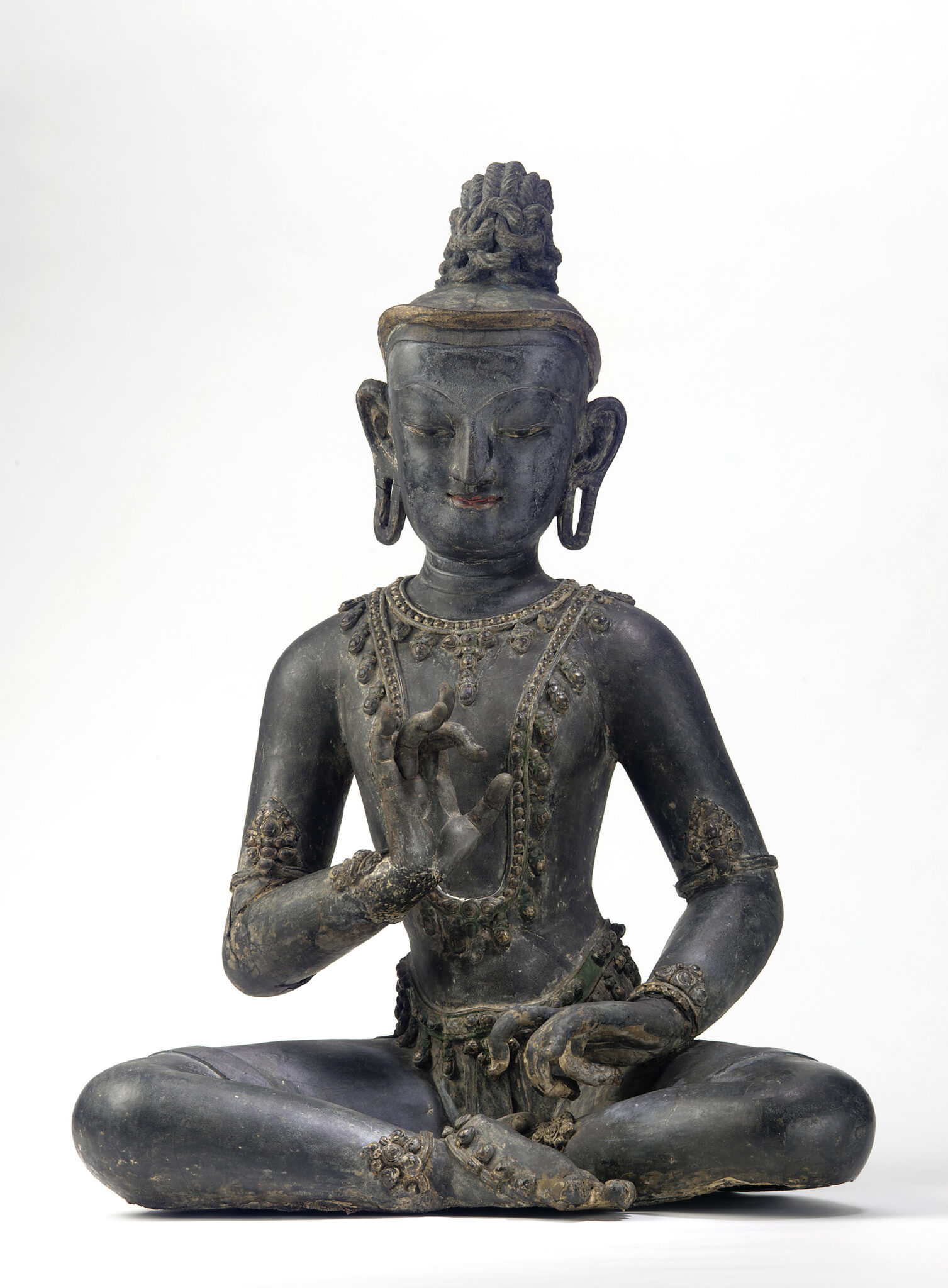 Dark brown seated Bodhisattva statue, chest inclined towards left with hands posed in mudras