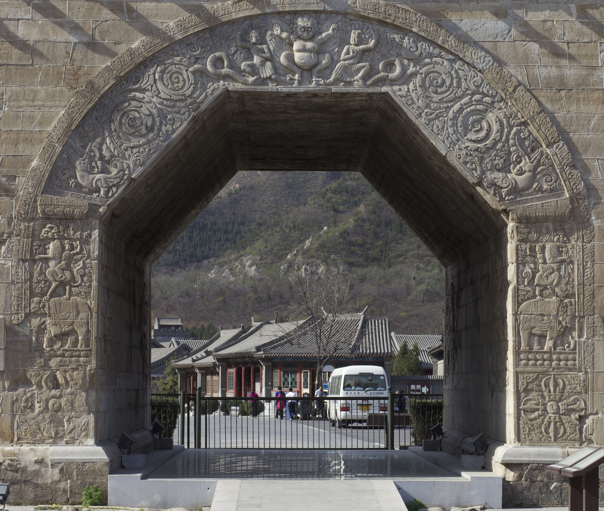 Monumental stone arch decorated with garuda, snake deities, scrollwork, mythical creatures, animals, and crossed vajras