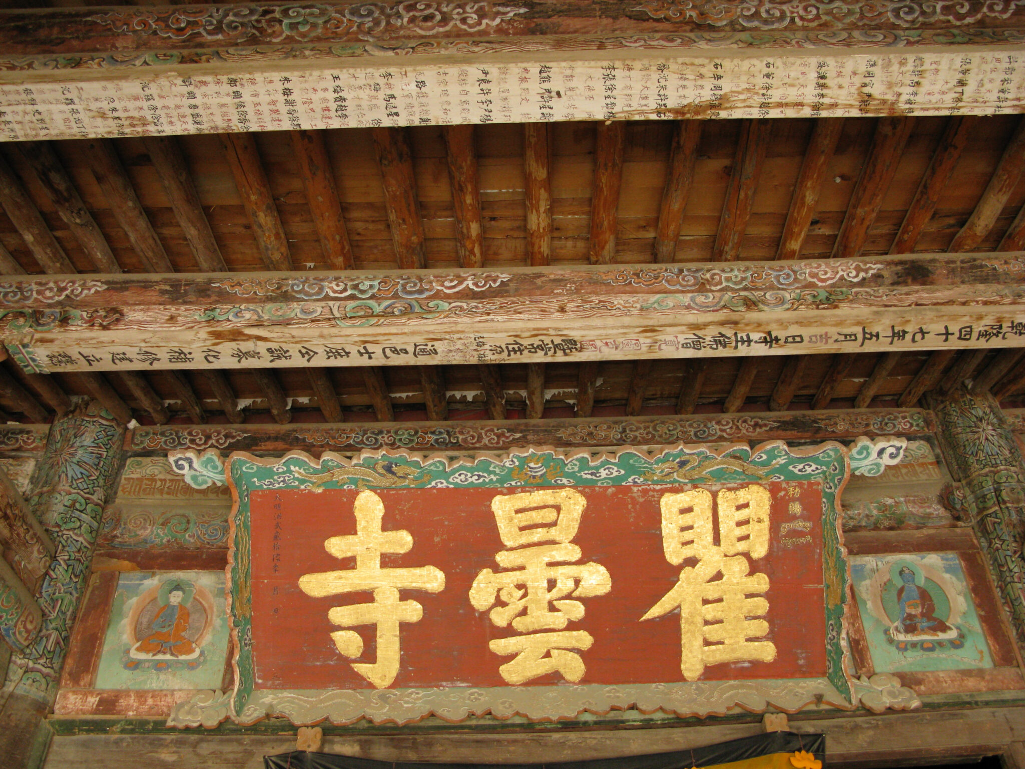Panel featuring three Chinese characters in gold against red background, flanked by two deity portraits