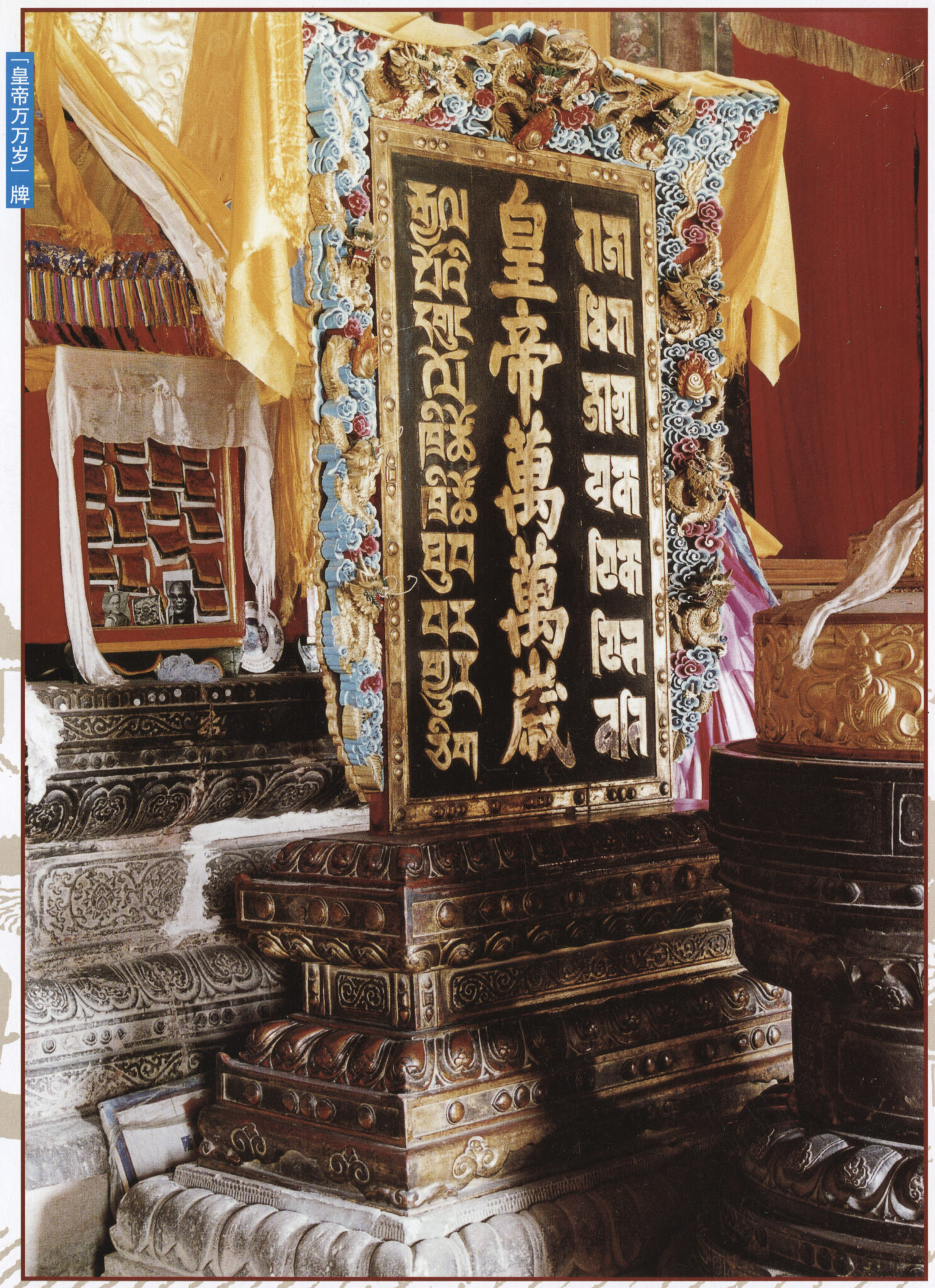 Black panel featuring inscription in Tibetan, Chinese, and Sanskrit; supported by polycrome gilt frame and stone base