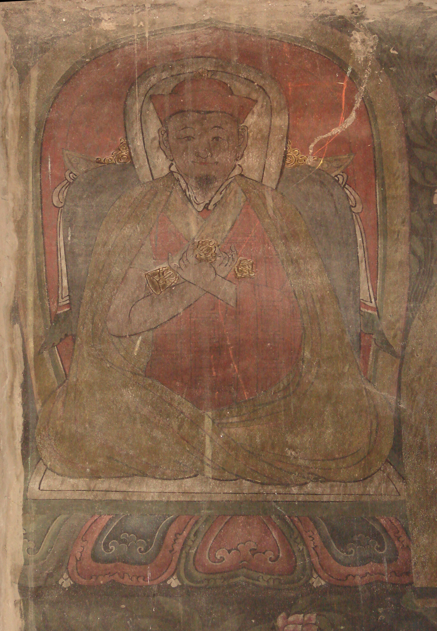 Detail of mural featuring yellow-robed figure crossing hands holding vajras at chest, seated on lotus