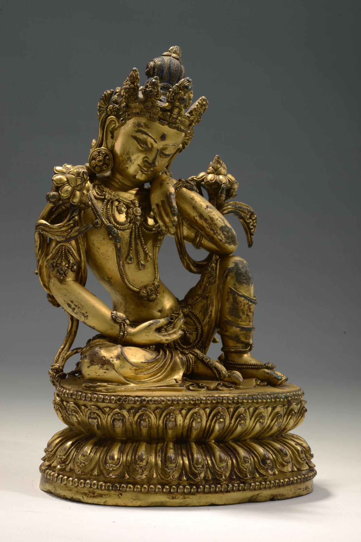 Gilded statuette of seated Bodhisattva with dramatically curved torso wearing elaborate crown and finely articulated accessories
