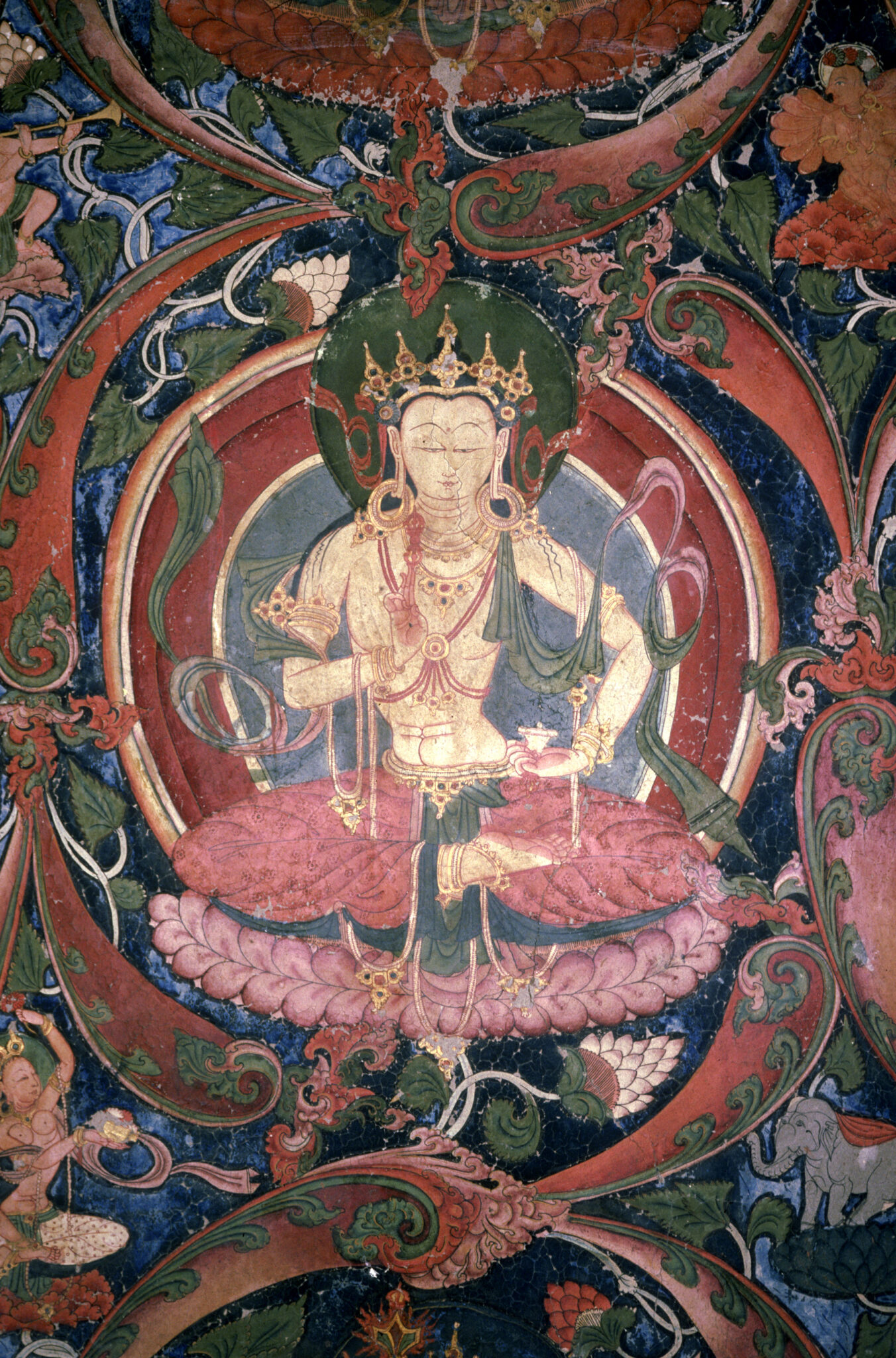 Crowned deity wearing pink dhoti seated on lotus, hands posed in mudras, within ovoid scrollwork border