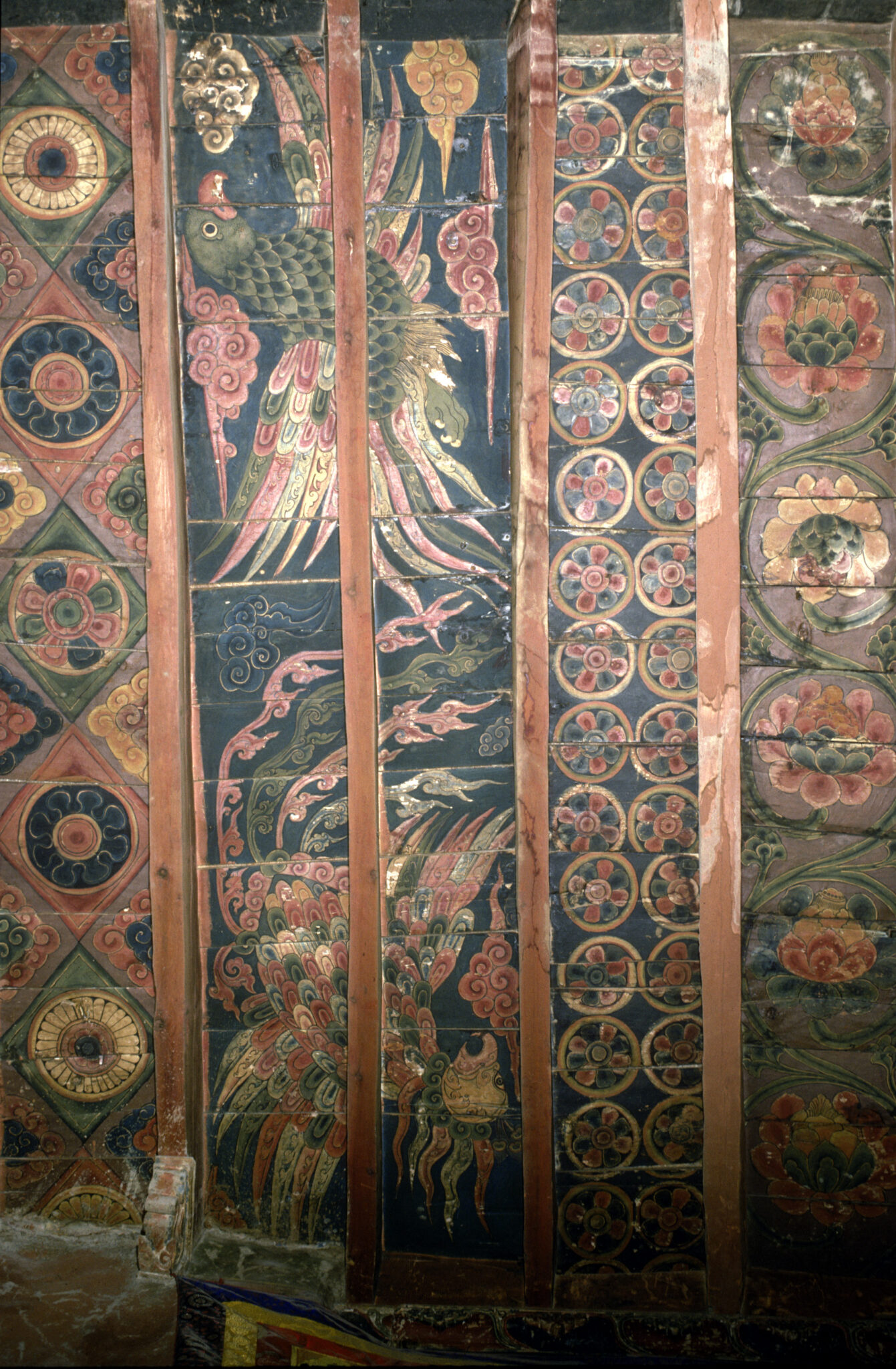Timber ceiling featuring richly decorated panels: geometric designs, two fantastical birds, roundels, and floral motifs