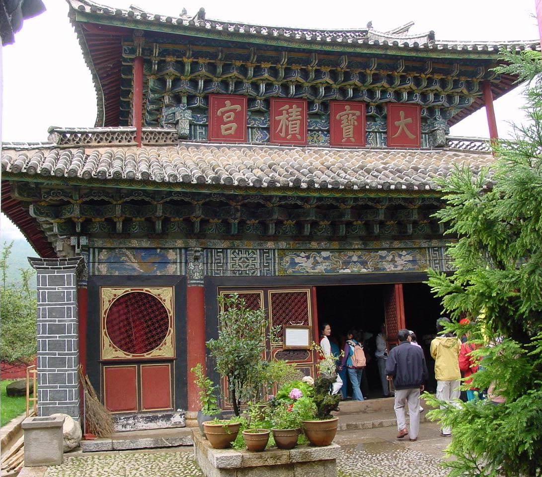 Wide view of richly painted temple entrance featuring double-pagoda roof and densely carved eaves