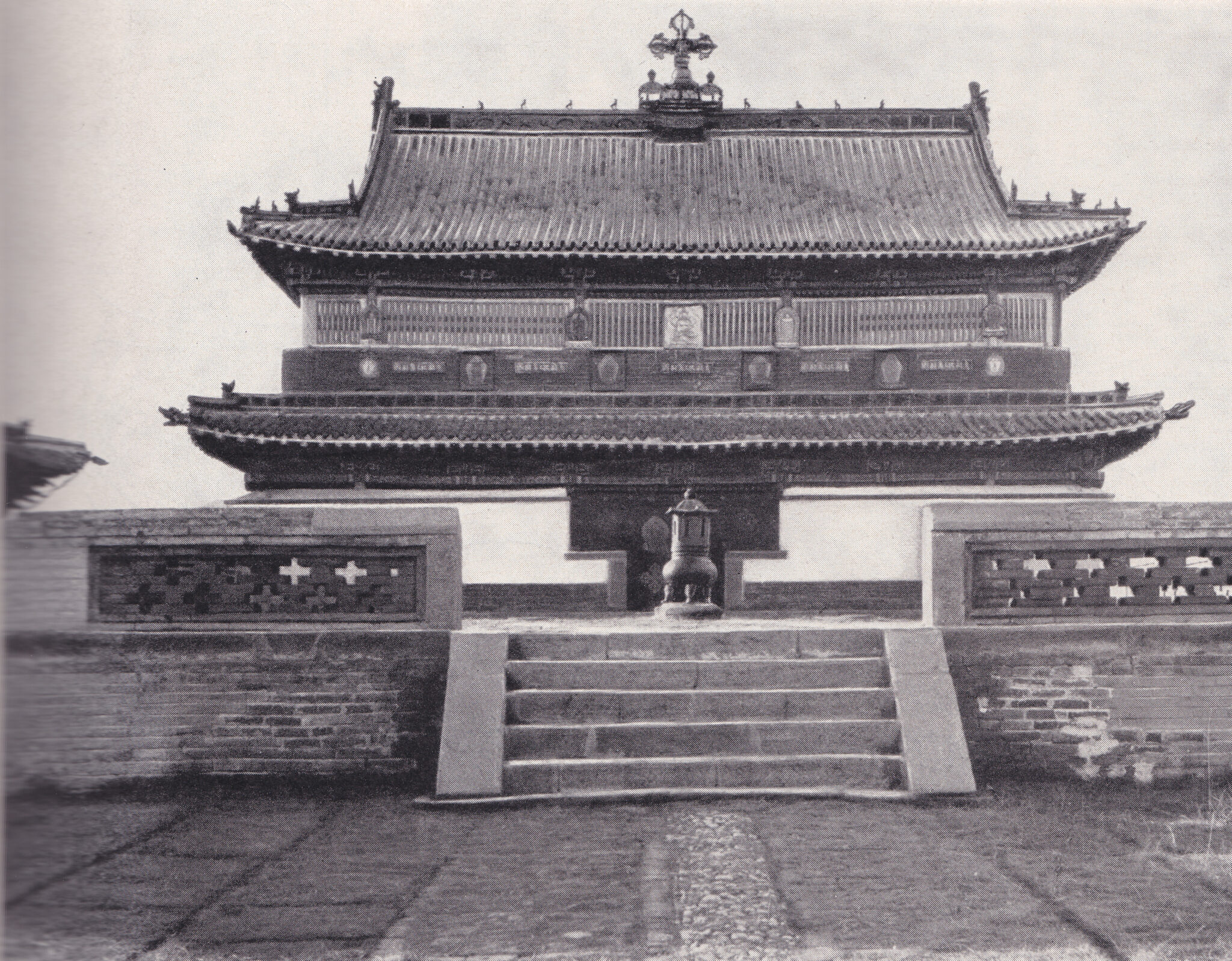 Black and white photograph of temple featuring tiered, pitched rooflines and crossed vajra at top