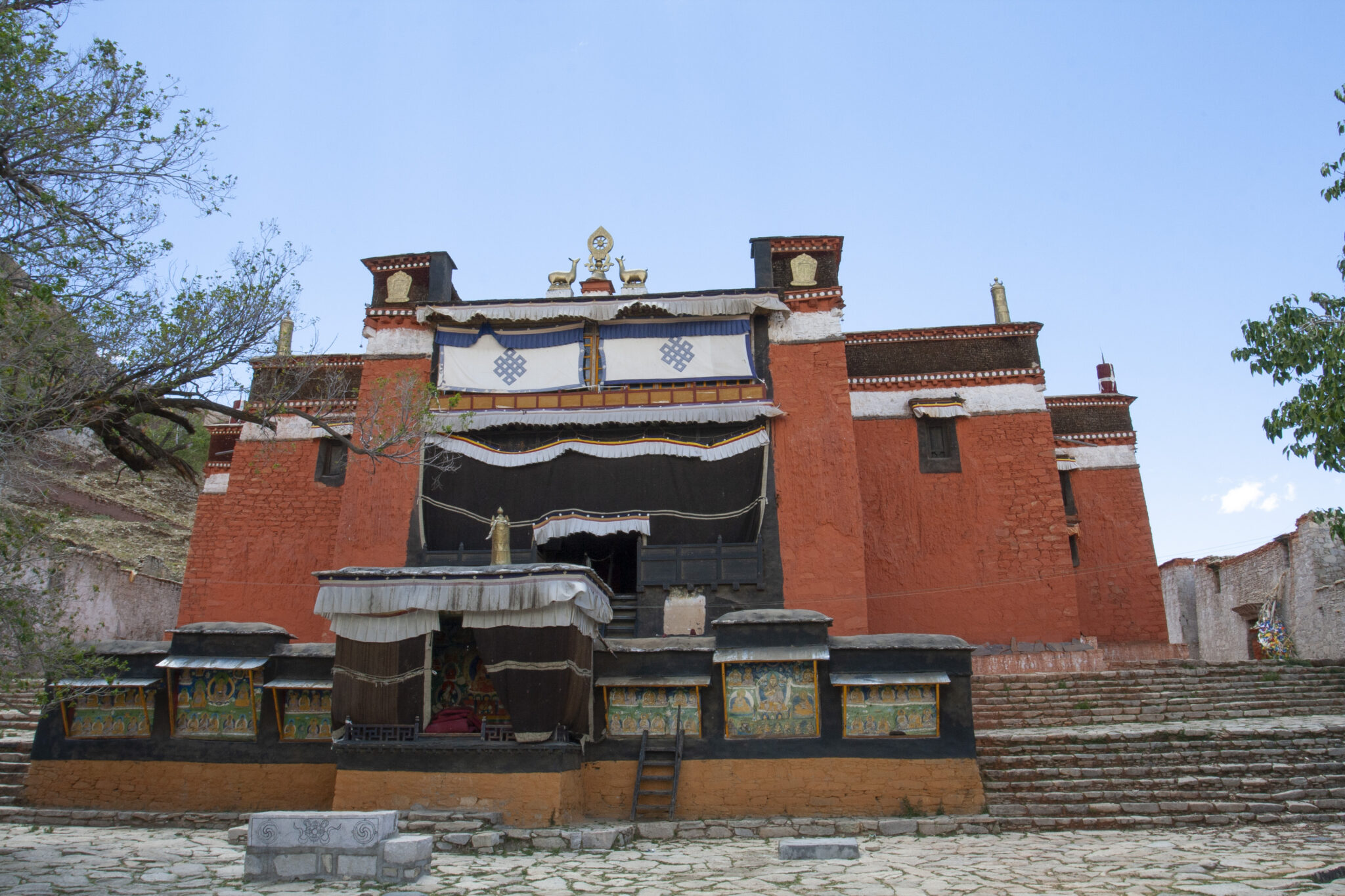 High-walled, rust-red temple with large banners hung above portal situated atop short staircase