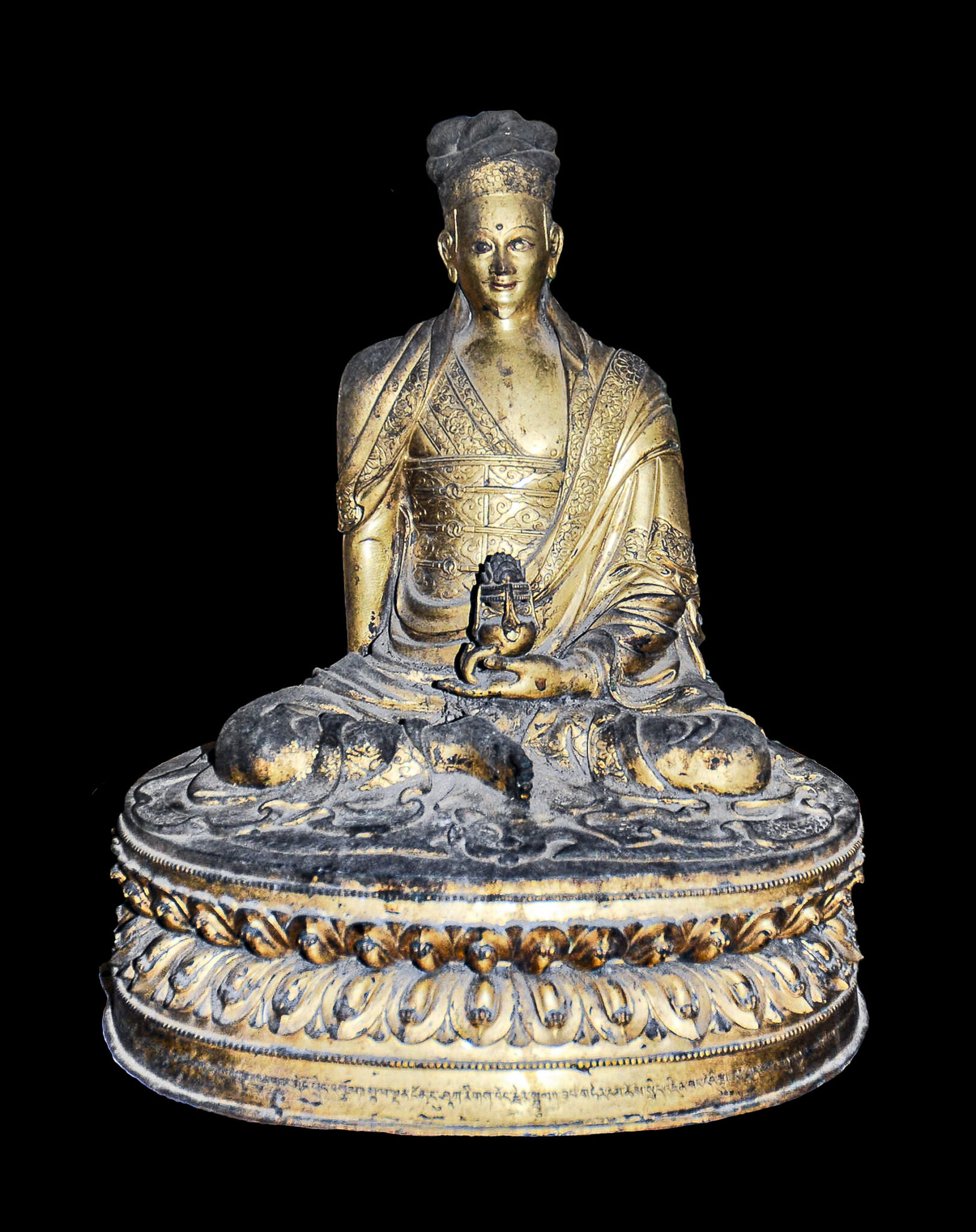 Tarnished golden statue depicting seated Siddha wearing gossamer robe holding implement in right hand