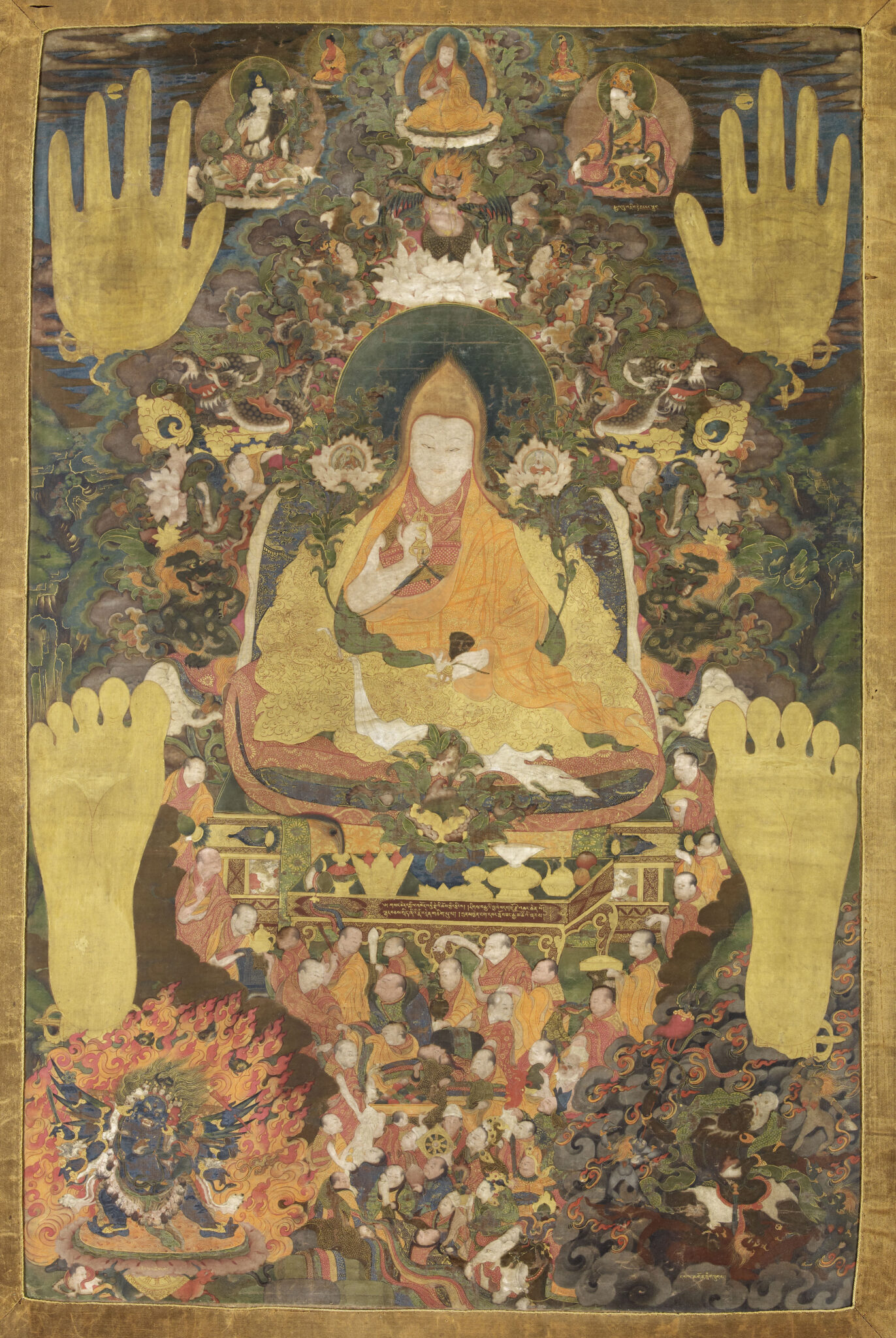 Two handprints and two footprints frame Dalai Lama seated above crowd of attendants and wrathful deity