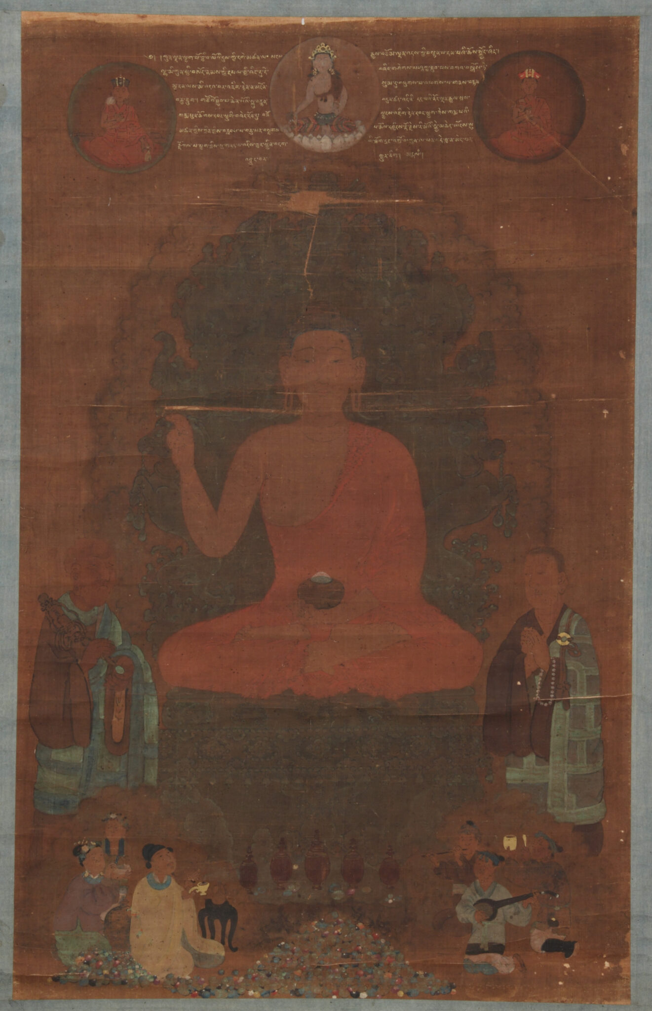Dusky brown painting depicting seated Buddha featuring text and deity portraits above, attendants assembled below