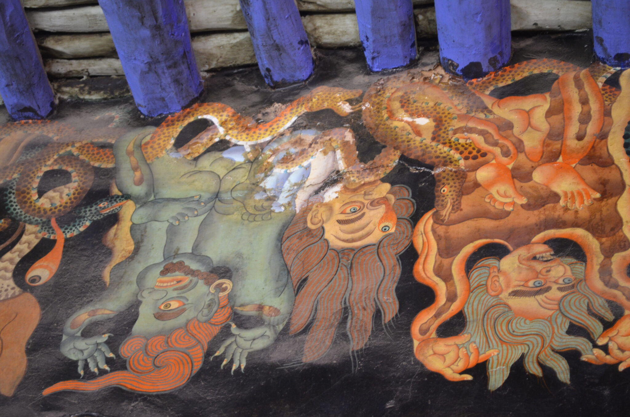 Mural depicting serpents and three flayed human skins painted to appear to hang from blue timber rafters