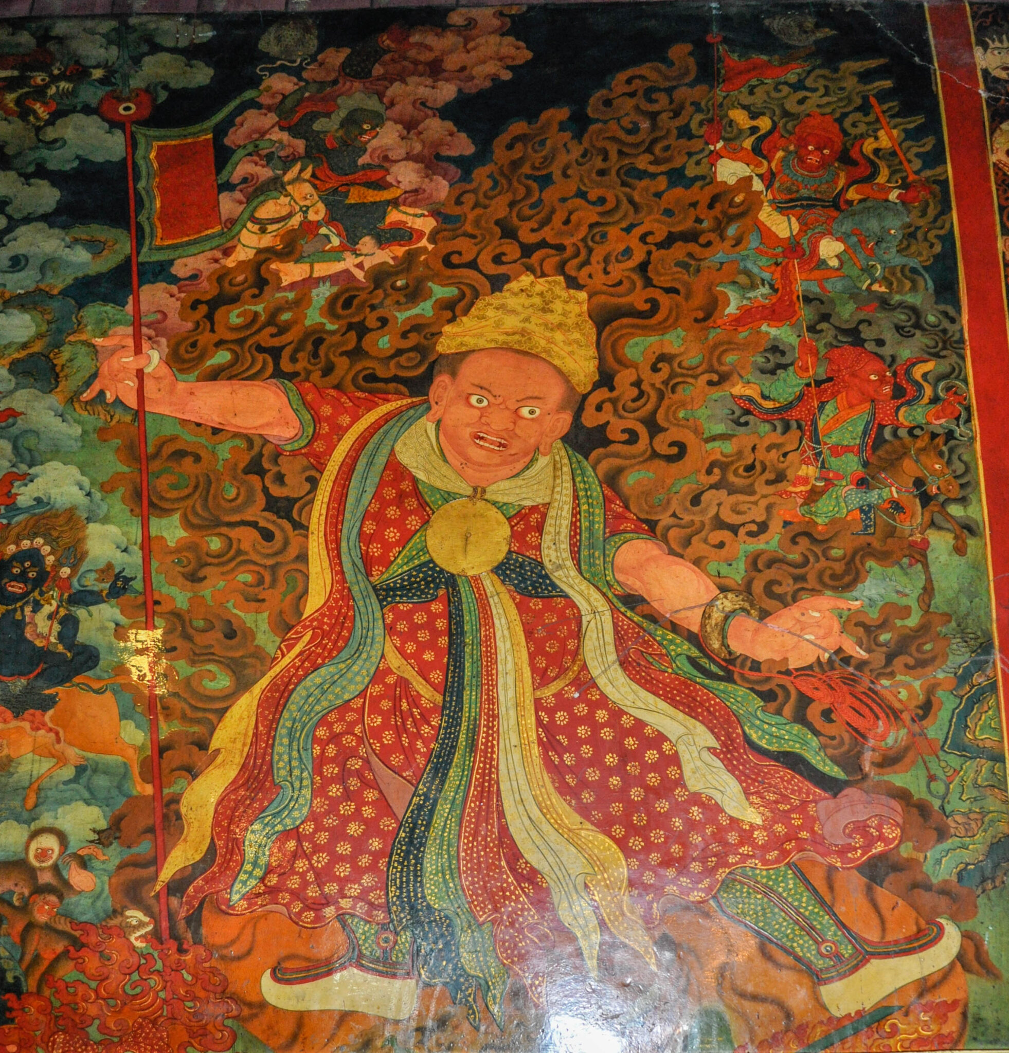 Mural depicting oracle outlined in flames wearing gold headdress, red and gold robe, and cascading ribbons