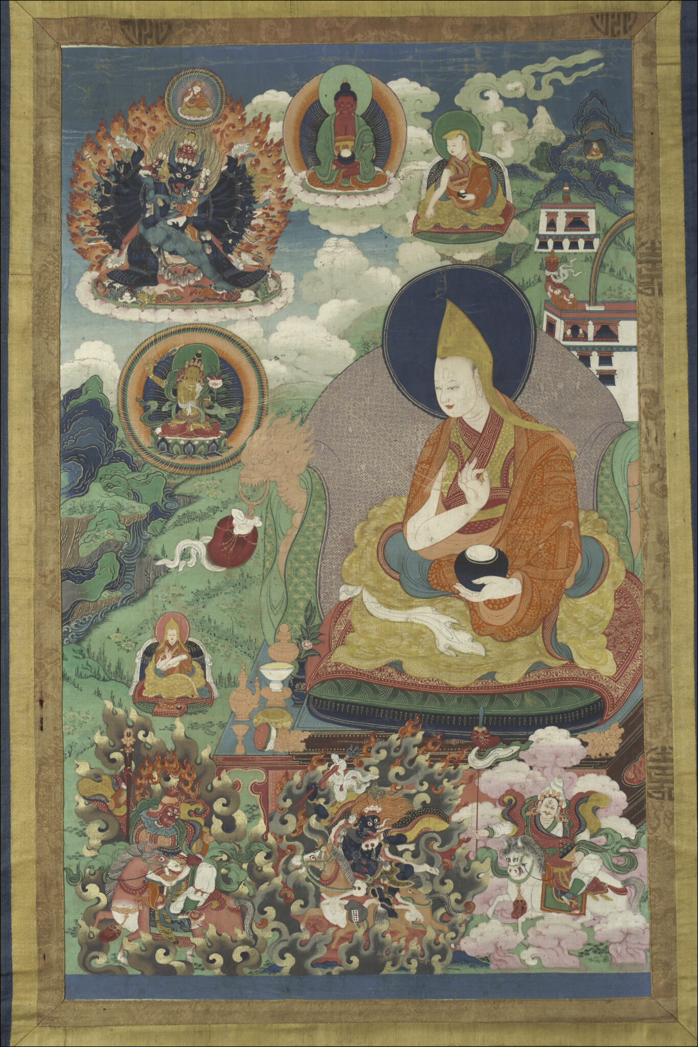 Lama enthroned outside of building complex on mountain spur, surrounded by deity and lama portraits