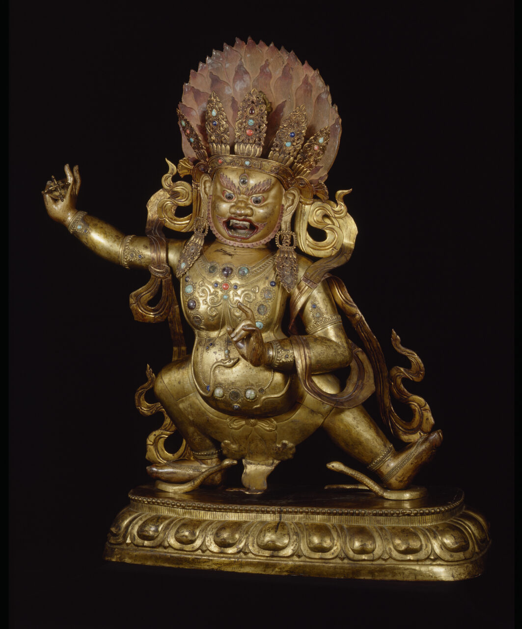 Golden-copper statue depicting wrathful crowned bodhisattva crouching in dynamic pose, holding vajra in outstretched left hand
