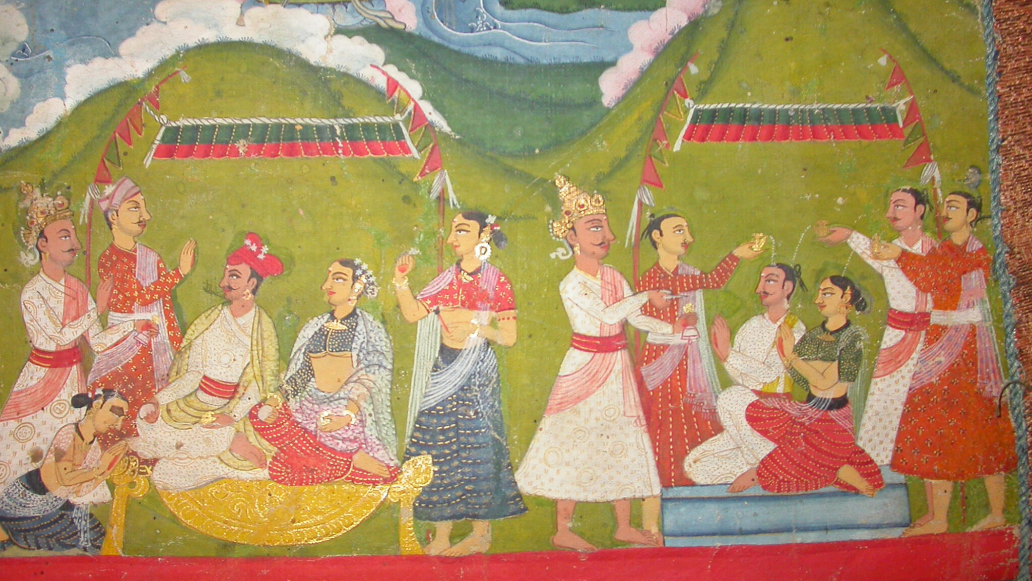 Two magnificently dressed couples, flanked by attendants, seated underneath canopies and deity portraits in mountain landscape