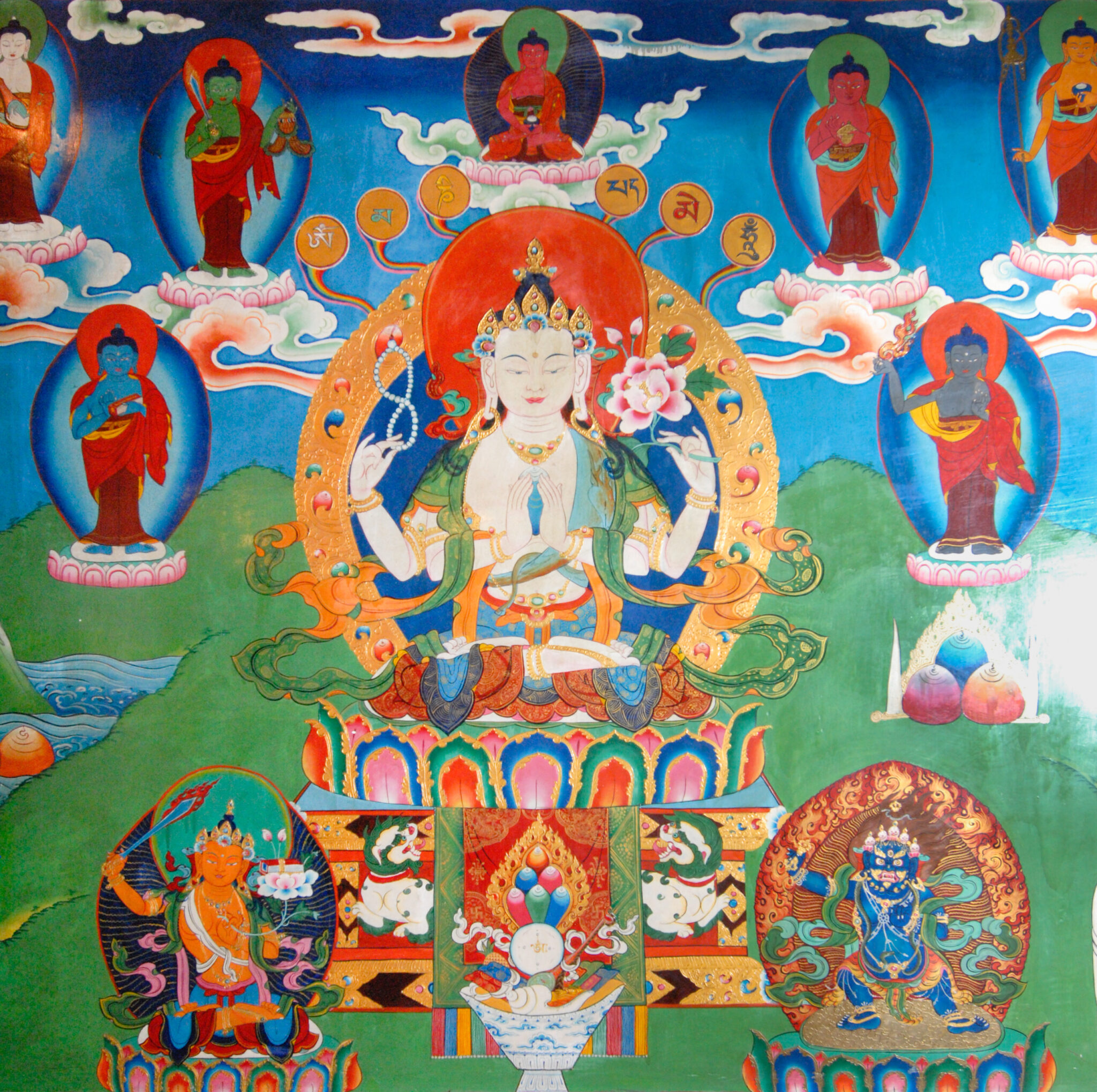 Bodhisattva seated on lotus pedestal at center, surrounded by Buddha and deity portraits, against mountainous background
