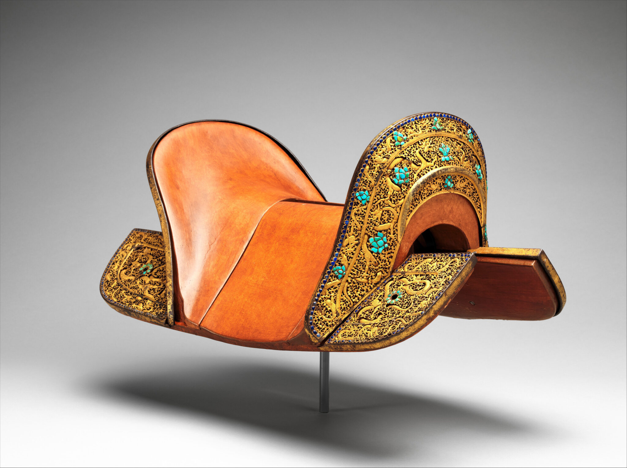 Orange leather saddle featuring gold filigree and turquoise decoration at pommel