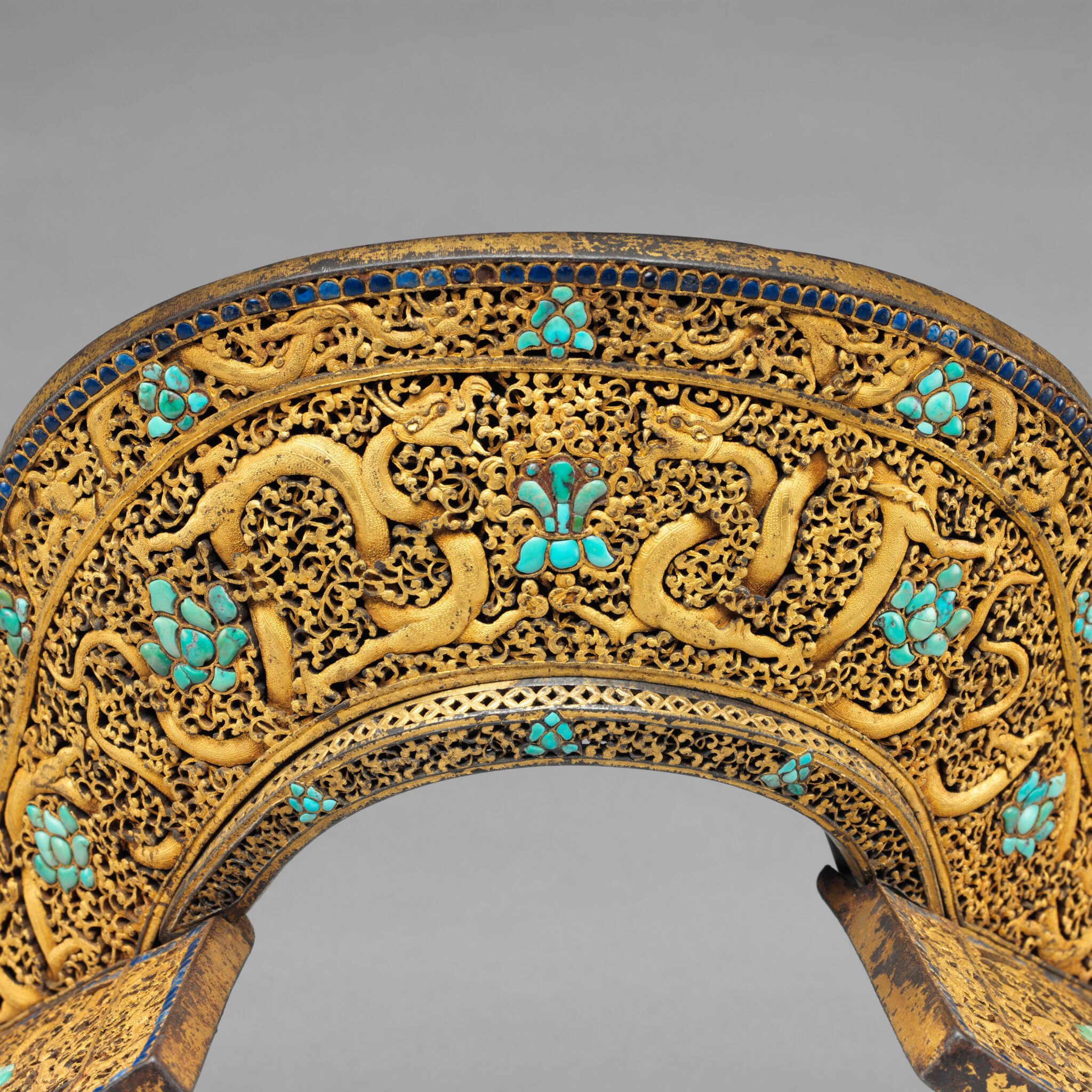Decoration on rear saddle plate depicting dragons writhing and twisting through field of golden filigree scrollwork