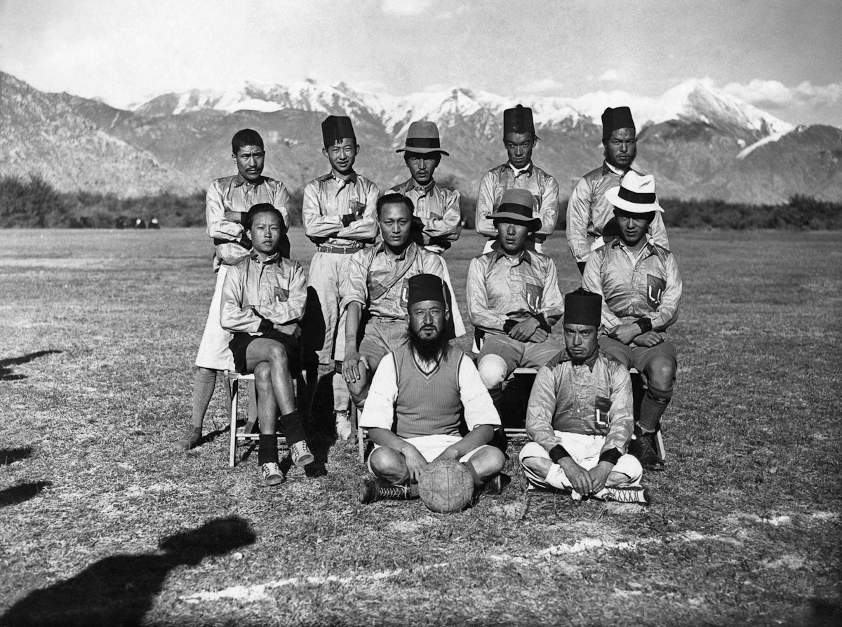 Black and white photograph of soccer team posing in three rows before mountain range