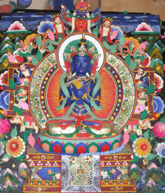 Close view of polychrome butter sculpture depicting blue-skinned deity seated before nimbus of flowers and mythological creatures
