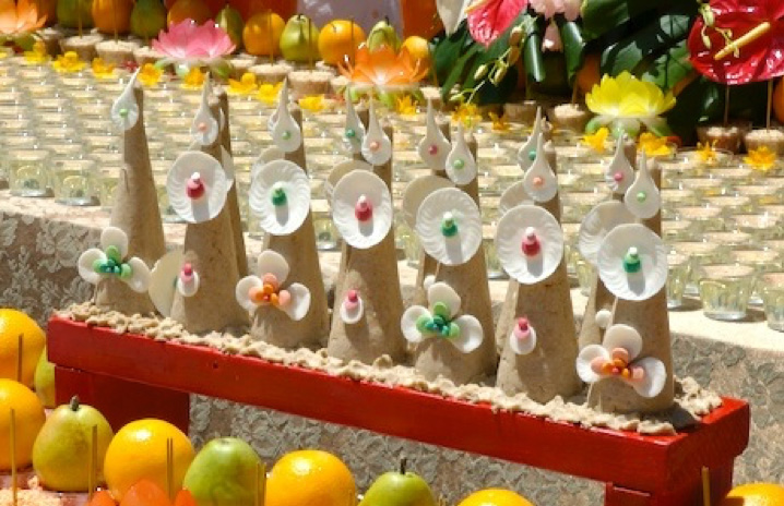 Devotional implements in the form of cones decorated with white, green, orange, and pink discs and petals