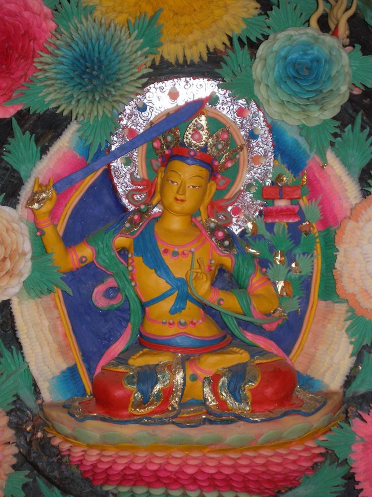 Colorful butter sculpture depicting Bodhisattva raising sword with left arm; holding right hand in mudra at chest