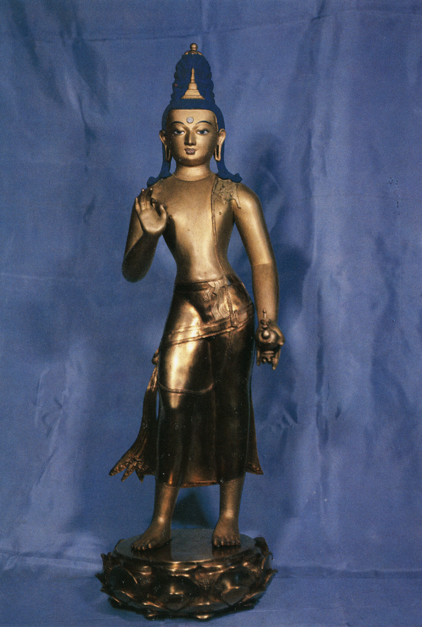 Golden Buddha with blue hair wearing diaphanous dhoti standing with left hand posed in mudra