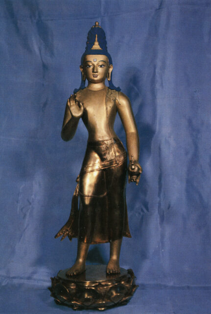 Golden Buddha with blue hair wearing diaphanous dhoti standing with left hand posed in mudra