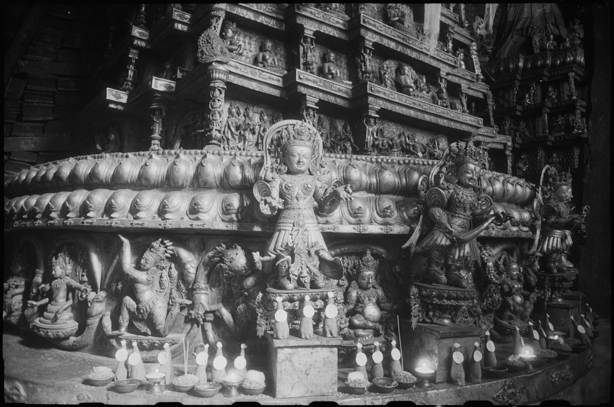 Black and white photograph of tapered structure surrounded at base by registers of decoration and deity statues
